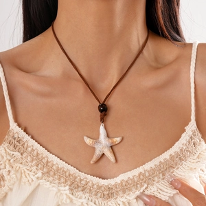 Détail du pendentif étoile de mer avec texture réaliste et cordon marron sur robe