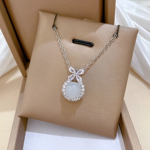 Close-up of silver titanium necklace with bowknot and white stone in a jewelry box