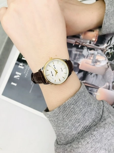 Detail of elegant ladies' watch with day-date display and brown leather strap on a wrist
