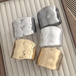 Detailed overhead view of wide metal bangles in gold, silver, and matte brushed finishes