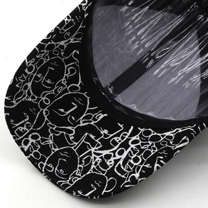 Detailed close-up of a black baseball cap featuring abstract white face print and PVC visor