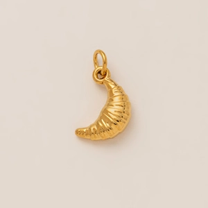 Detailed macro shot of a golden croissant-shaped pendant with 18K gold-plated finish