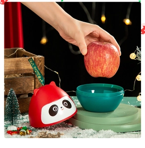 Close-up of panda-shaped Christmas apple gift box with green ribbon and festive decor