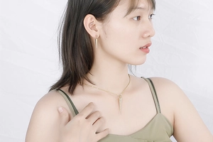 Detail of a gold conical spiral jewelry set with zircons on a female model