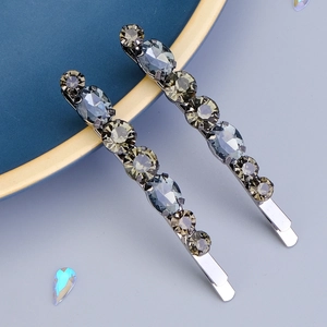 Détail de barrettes en métal avec des strass gris foncé et fumés sur une assiette
