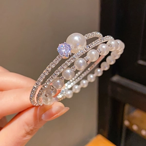 Detail of a three-layer silver bracelet featuring pearls and purple zircon stones