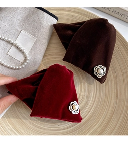 Close-up of velvet camellia hair claws with pearl gold accents in burgundy and coffee brown