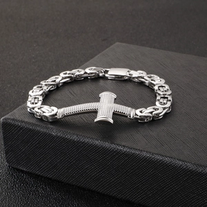 Macro detail of silver stainless steel cross bracelet on a textured black gift box