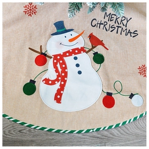 Detail of Christmas tree skirt featuring snowman and red bird on linen texture