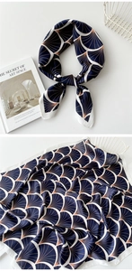 Detail of silk square scarf featuring navy blue fan patterns and soft drape texture