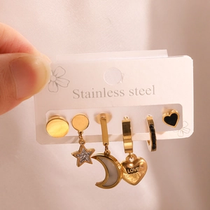 Macro detail of six gold stainless steel earrings featuring star, moon and love charms