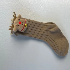 Detail of coffee brown ribbed knit sock featuring a 3D plush reindeer with golden antlers