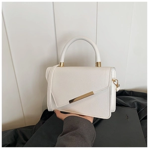 Detailed close-up of white lychee texture leather handbag with gold metal bar and top handle