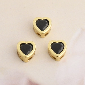 Detailed view of three golden heart-shaped pendants with black cubic zirconia stones