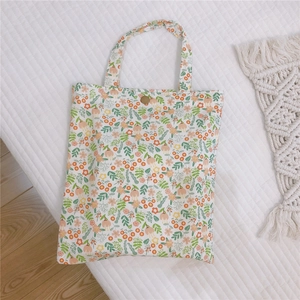Détail d'un mini sac en toile à fleurs avec fermeture par un bouton en métal rétro