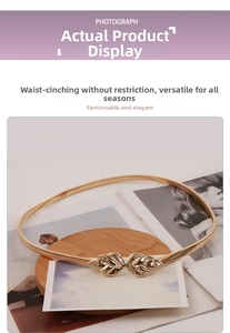 Detailed view of elastic gold metal chain belt with leaf buckle on a wooden tray