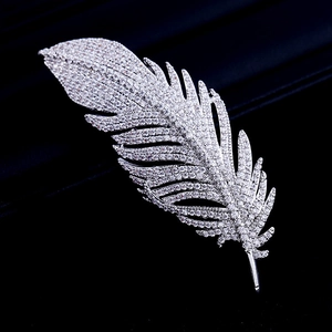 Detailed view of feather-shaped brooch with sparkling cubic zirconia on silver metal