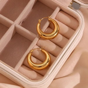 Detail of 25mm hollow 18K gold plated stainless steel hoops in a beige jewelry box