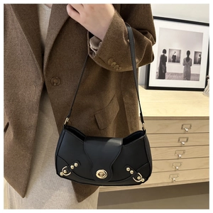 Close-up of black shoulder bag with gold metal hardware and rivet details on suit jacket