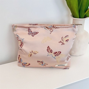 Detail of light pink jacquard fabric bag with colorful butterfly embroidery and metal zipper