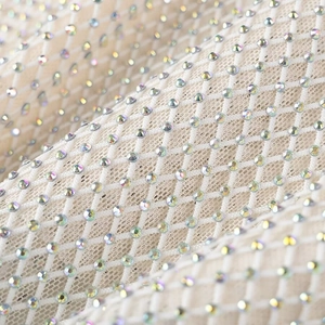 Macro d'un tissu résille blanc avec des strass multicolores brillants sur une robe