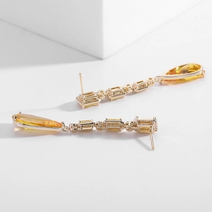 Macro detail of gold-plated drop earrings with pear-cut yellow zircon and rectangular stones