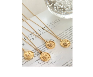 Detail view of gold-plated necklaces with round sun and moon coin pendants and zircons