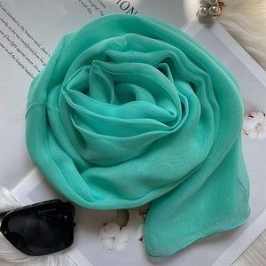 Macro detail of mint green chiffon scarf rolled as a rose with soft pleats and texture