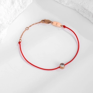 Détail du bracelet en corde rouge avec pendentif lettre K or rose et pierre de zircon ronde