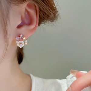 Elegant bow and flower stud earrings with purple crystals and pearls on model