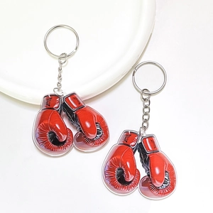 Creative red acrylic boxing glove keychains with silver metal chains on a white plate