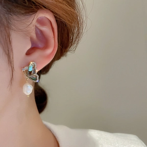 Macro detail of butterfly earring featuring baroque pearl and sparkling zircons