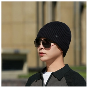Close-up of black ribbed knit beanie featuring a small mountain-shaped metal logo plate