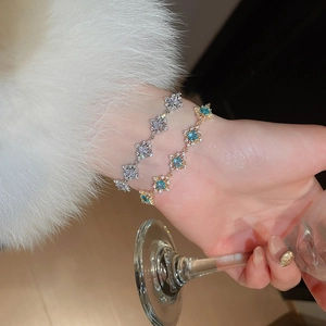 Detailed view of silver and gold geometric bracelets with square blue zircon stones