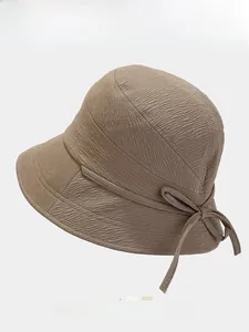 Detail of khaki bucket hat showing woven ripple texture and matching side bow decoration