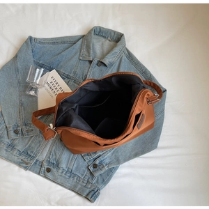Top view of caramel nylon tote bag interior with functional pockets and denim outfit