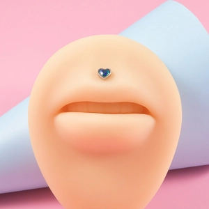 Close-up of heart-shaped blue opal labret piercing on a silicone model mouth