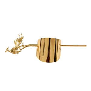 Detail of golden metal hair cuff with intricate phoenix design and matching hair pin