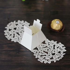 Macro shot of white hollow butterfly paper favor box with chocolate scale reference