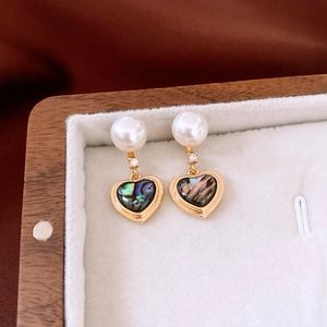 Détail de boucles d'oreilles vintage cœur avec perle, zircon et nacre d'ormeau