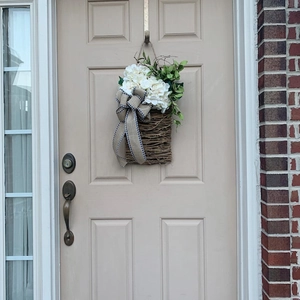 Detail of a door hanging basket with white hydrangeas and a burlap bow on a door