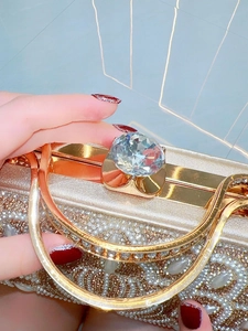Macro shot of gold evening bag featuring luxury rhinestones and pearl embellishments