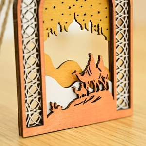Detailed wood carving of a mosque and camels in an arched wooden holiday ornament