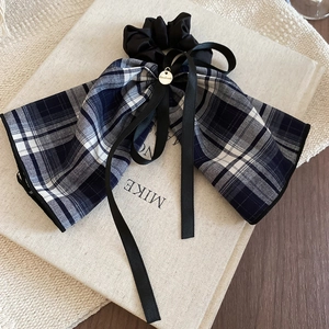 Detail of blue plaid fabric bow with black satin ribbon and gold handmade pendant charm