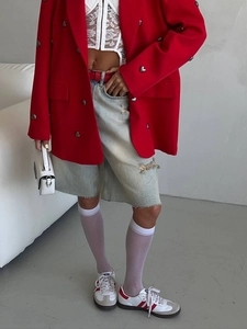 Red mid-length blazer with heart buttons and lace top on a model in industrial studio