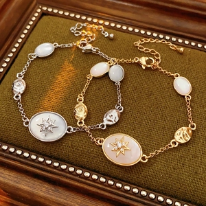 Macro detail of gold and silver oval starburst bracelets on dark green velvet