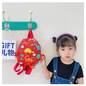 Close-up of red children backpack with colorful dinosaur prints hanging on a green rack