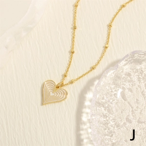 Detail of a gold heart pendant necklace with white enamel concentric circles and bead chain