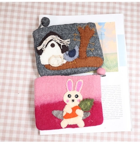 Detail of handmade felt coin purses with stitched trees, birds, and cute rabbit embroidery