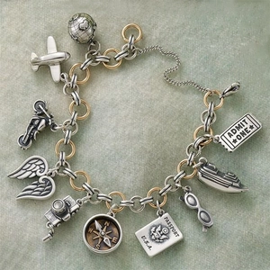 Macro detail of silver and gold travel themed bracelet charms including passport and airplane